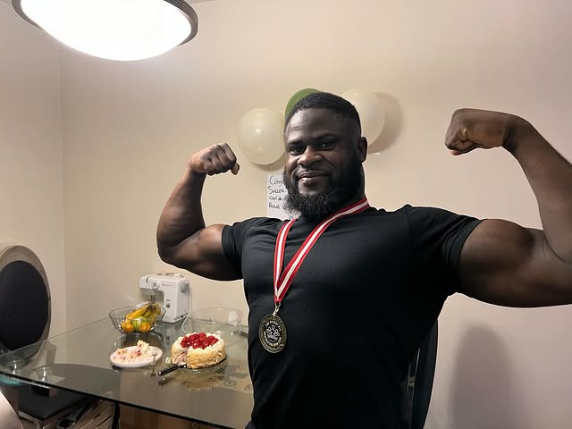 Coach Hamza Touray flexing with a competition medal